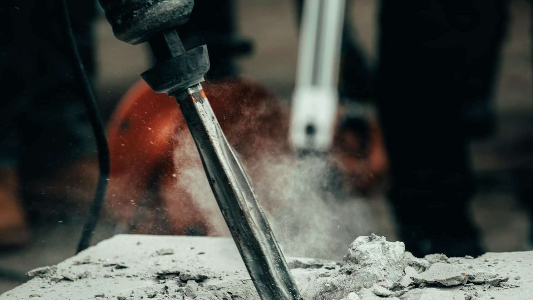 A detailed close-up of a power tool chipping away at a concrete block, capturing action and dust.